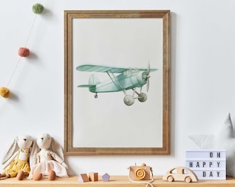 May include: A framed watercolor painting of a light blue airplane with a brown wooden frame. The painting is hanging on a white wall with a string of colorful pom-poms hanging above it.