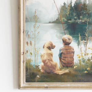 May include: Framed art print depicting a boy and a golden retriever dog fishing by a lake. The boy wears a plaid shirt, and the dog sits beside him. The artwork has a soft, painterly style with a serene, natural setting.
