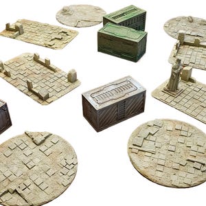 Könnte beinhalten: Eine Sammlung von Miniatur-Geländeteilen für Tabletop-Spiele. Enthält rechteckige und kreisförmige Plattformen sowie mehrere kastenförmige Strukturen. Die Teile sind hauptsächlich beige und braun und haben ein strukturiertes, steinartiges Aussehen.