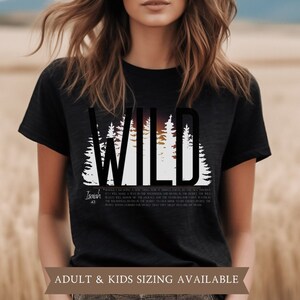 May include: Black t-shirt with the word "WILD" in large, bold letters above a silhouette of pine trees and a sunset. The text "Isaiah 43" is below the trees. The shirt is available in adult and kids sizes.