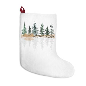 May include: White Christmas stocking with a watercolor illustration of a row of evergreen trees and the text "A Thrill of Hope".