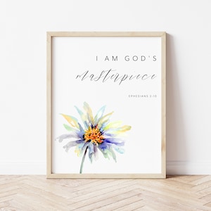 Puede incluir: Un cuadro enmarcado con el texto "I AM GOD'S masterpiece" y "Efesios 2:10". La obra presenta una flor de acuarela en tonos azules, amarillos y naranjas. El marco es de color madera clara y el fondo es blanco.