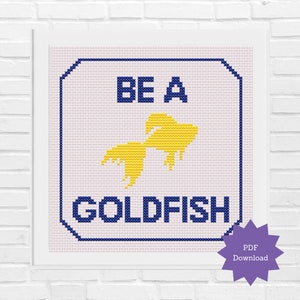 Peut inclure: Une œuvre d'art au point de croix avec les mots "BE A GOLDFISH" en bleu marine, avec un motif de poisson rouge jaune. Le design est encadré dans un cadre carré blanc. Une icône de téléchargement PDF violette est dans le coin inférieur droit.