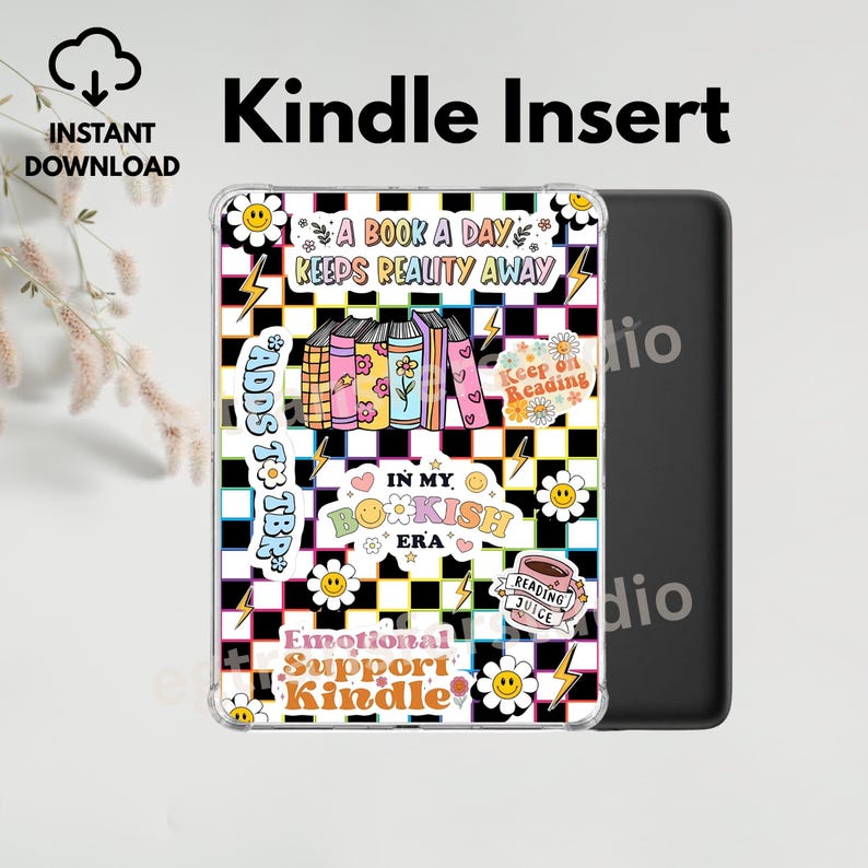Op de afbeelding: Een transparante Kindle-hoes met een kleurrijk ontwerp met boeken, madeliefjes en bliksemschichten op een zwart-witte geruite achtergrond. Tekst bevat "A Book A Day Keeps Reality Away" en "Emotional Support Kindle."