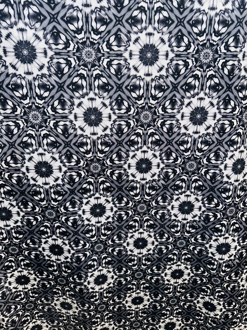 May include: Black and white fabric with a repeating geometric pattern. The pattern features a series of interlocking circles and squares.