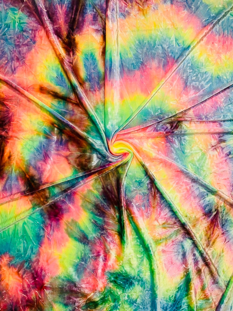 May include: A vibrant, tie-dye fabric with a swirling pattern. The colors include shades of green, yellow, orange, pink, blue, and purple. The fabric is folded and gathered in the center, creating a spiral effect. The overall effect is bright and colorful.