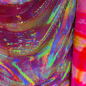 May include: A close-up of iridescent pink fabric with a holographic finish. The fabric has a textured, honeycomb pattern and is draped in a way that shows off its shimmery quality.