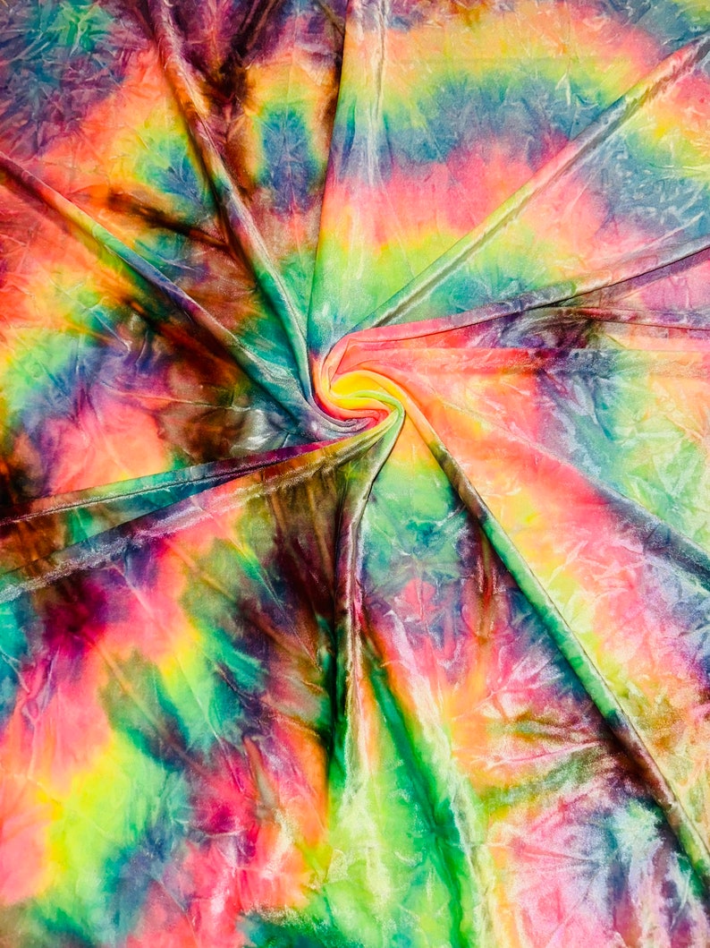 May include: A vibrant, multi-colored fabric with a tie-dye pattern. The colors include shades of pink, yellow, green, blue, and purple. The fabric is swirled and folded, creating a dynamic and textured appearance. The overall effect is bright and eye-catching.