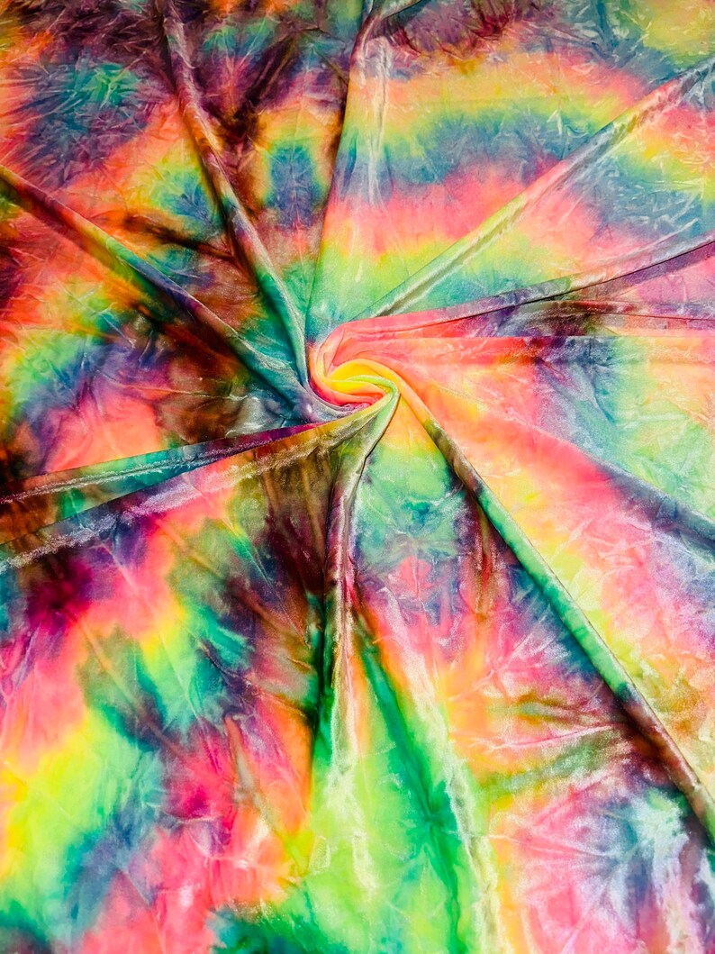 May include: A vibrant, tie-dye fabric with a swirling pattern. The fabric features a blend of colors, including pink, yellow, green, blue, and orange. The material appears soft and has a slight sheen, with visible folds and creases.