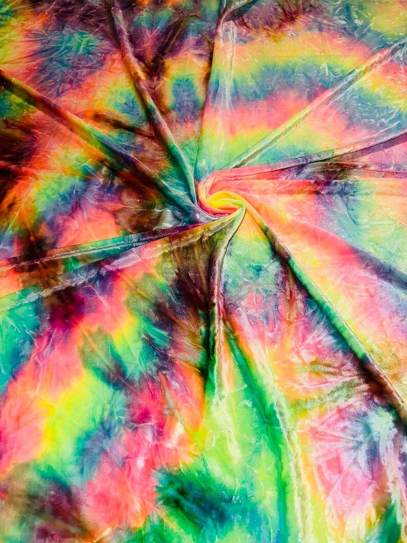 May include: A vibrant, swirled fabric with a tie-dye pattern. The colors include shades of pink, yellow, green, blue, and purple. The fabric is gathered in the center, creating a spiral effect. The material appears soft and flowing.
