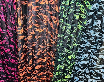 Puede incluir: Primer plano de tres piezas de tela de malla negra con un patrón de llamas. La tela está plisada y las llamas son de diferentes colores: rosa, naranja y azul.