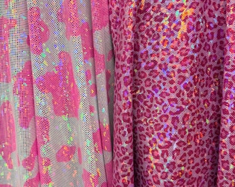 May include: Close-up of two different fabrics. One is a pink and white mesh with large pink shapes. The other is a shiny pink fabric with a leopard print pattern. Both fabrics have a holographic sheen.