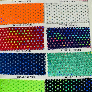 Pode incluir: Um livro de amostras de tecido com diferentes cores e padrões. O tecido é um veludo com lantejoulas prateadas em um padrão de bolinhas. As cores são amarelo, rosa, laranja, branco, vermelho, roxo, azul royal, verde, verde limão e preto.