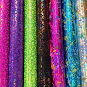 Puede incluir: Varios rollos de tela en colores vibrantes. Las telas presentan estampados de leopardo en tonos rosa, morado, verde y negro. Otras telas tienen un dise&ntilde;o de salpicaduras en tonos rosa, azul y dorado.