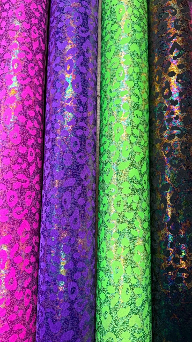Puede incluir: Cuatro rollos de tela con un dise&ntilde;o de estampado de leopardo. Los rollos son en tonos de rosa, morado, verde y negro. La tela tiene un acabado brillante y hologr&aacute;fico.