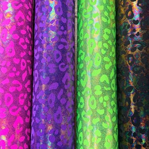 Puede incluir: Cuatro rollos de tela con estampado de leopardo. Los colores incluyen rosa intenso, morado, verde ne&oacute;n y un color oscuro iridiscente. La tela tiene una superficie brillante y texturizada.