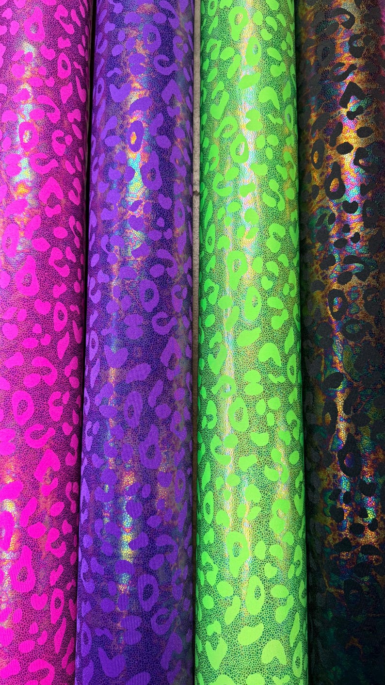 Puede incluir: Cuatro rollos de tela con estampado de leopardo. Los colores incluyen rosa intenso, morado, verde ne&oacute;n y un color oscuro iridiscente. La tela tiene una superficie brillante y texturizada.