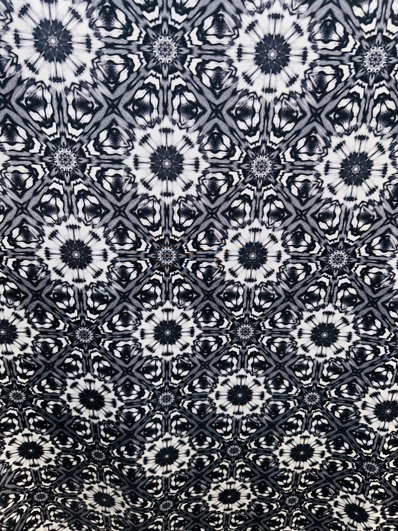 May include: Black and white fabric with a repeating pattern of stylized flowers and geometric shapes.