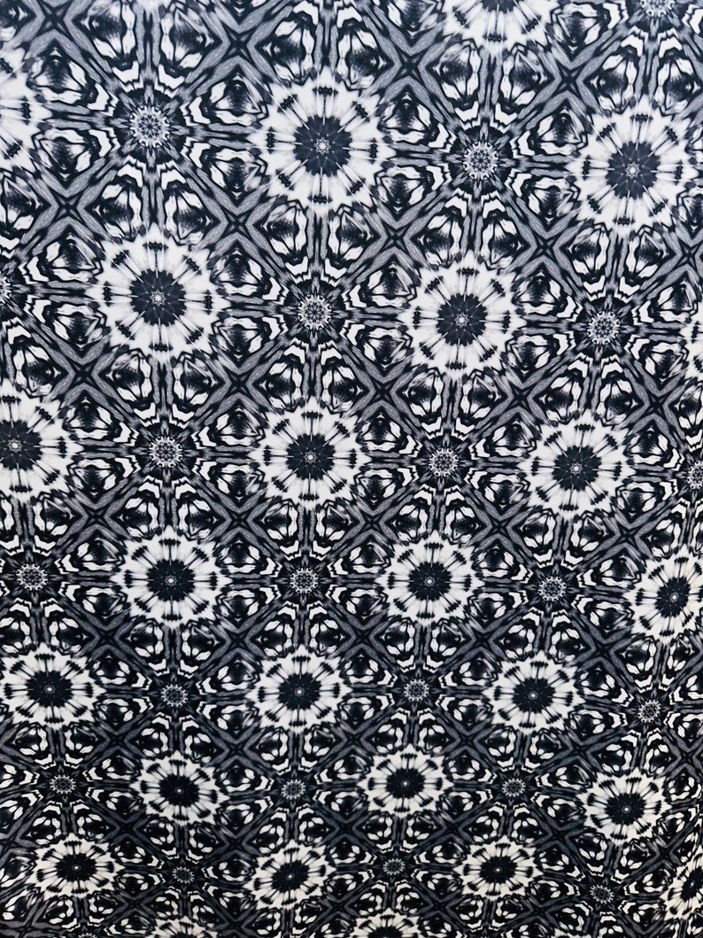 May include: Black and white fabric with a repeating geometric pattern. The pattern features a series of interlocking stars and diamonds.