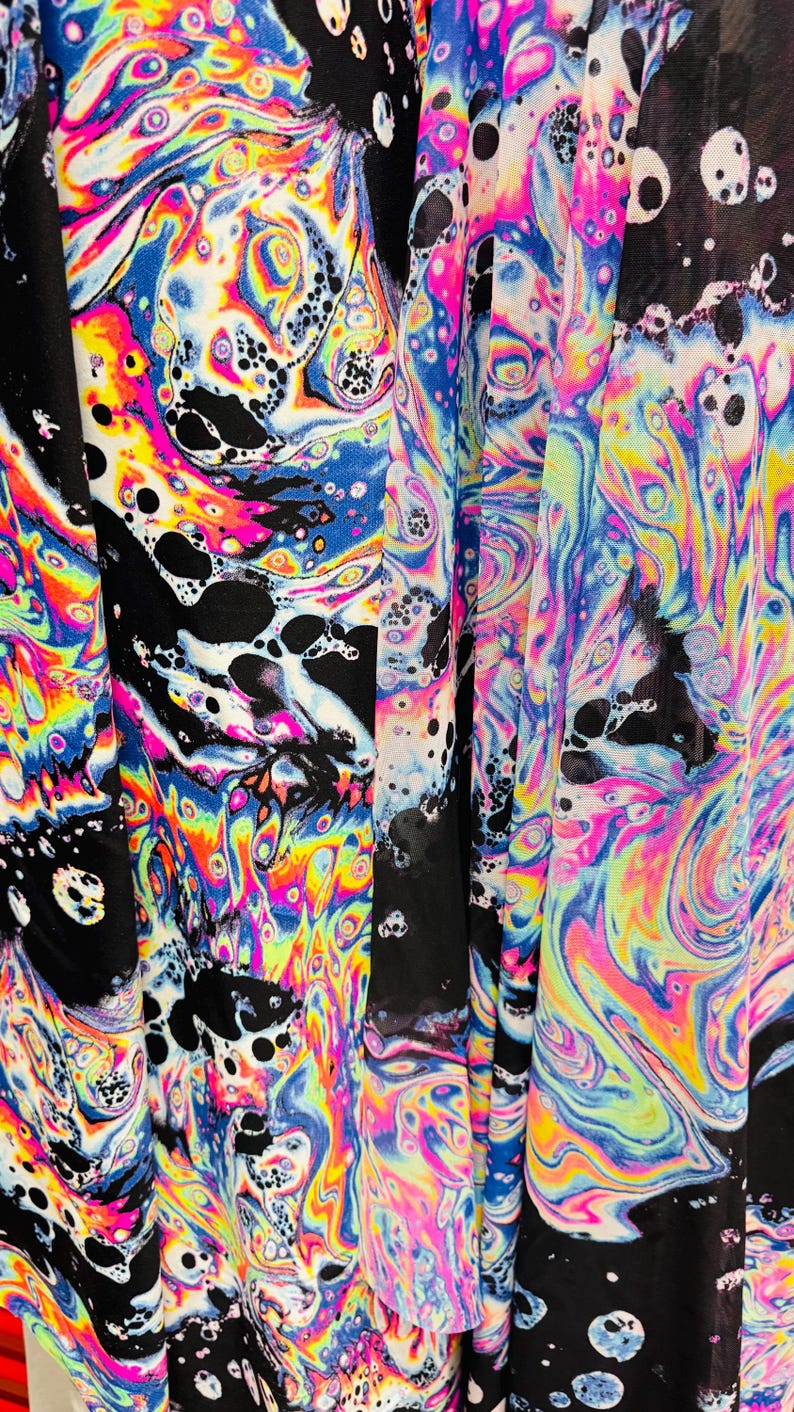 Puede incluir: Tela negra transparente con un patr&oacute;n de remolino iridiscente de colores. La tela tiene una textura de malla y es perfecta para manualidades o para hacer ropa.