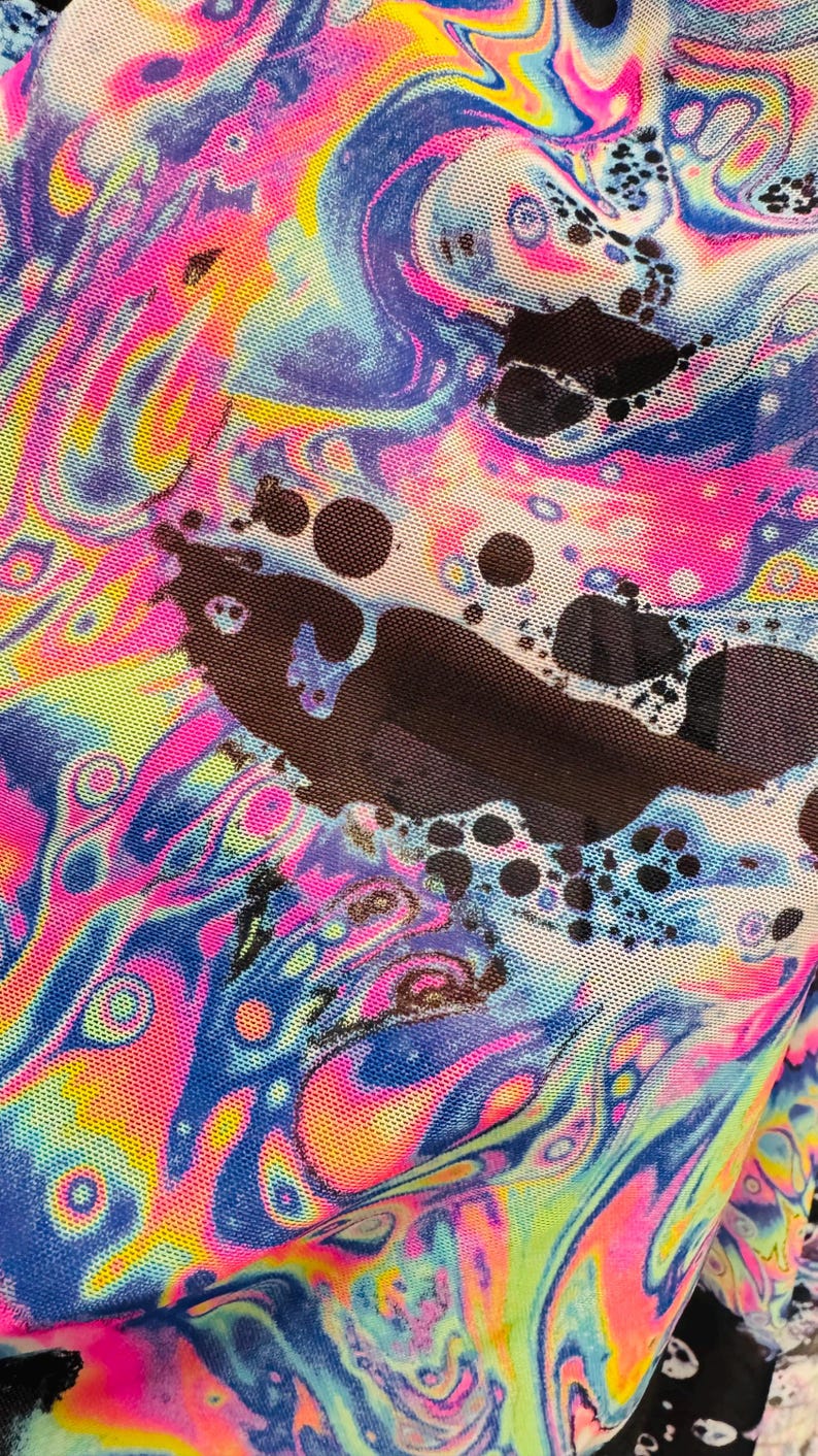 Puede incluir: Primer plano de una tela colorida con un patr&oacute;n abstracto en espiral en tonos de rosa, azul, amarillo y verde. La tela tiene una textura de malla y est&aacute; superpuesta con puntos negros.