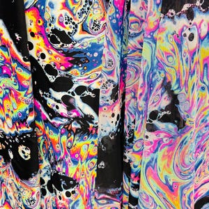 Puede incluir: Una tela negra con un patr&oacute;n psicod&eacute;lico colorido, similar a una mancha de aceite. La tela tiene una textura de malla.