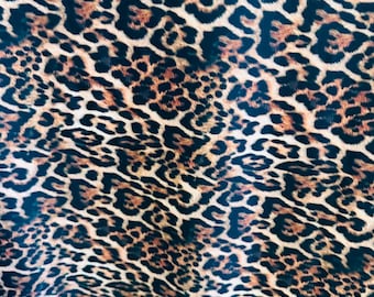 May include: A close-up of a fabric with a leopard print pattern. The fabric is brown, black, and white.