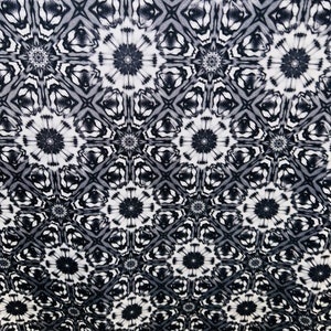 May include: Black and white fabric with a repeating geometric pattern of stylized flowers. The pattern is a gradient, with the flowers becoming more defined and darker at the bottom of the fabric.
