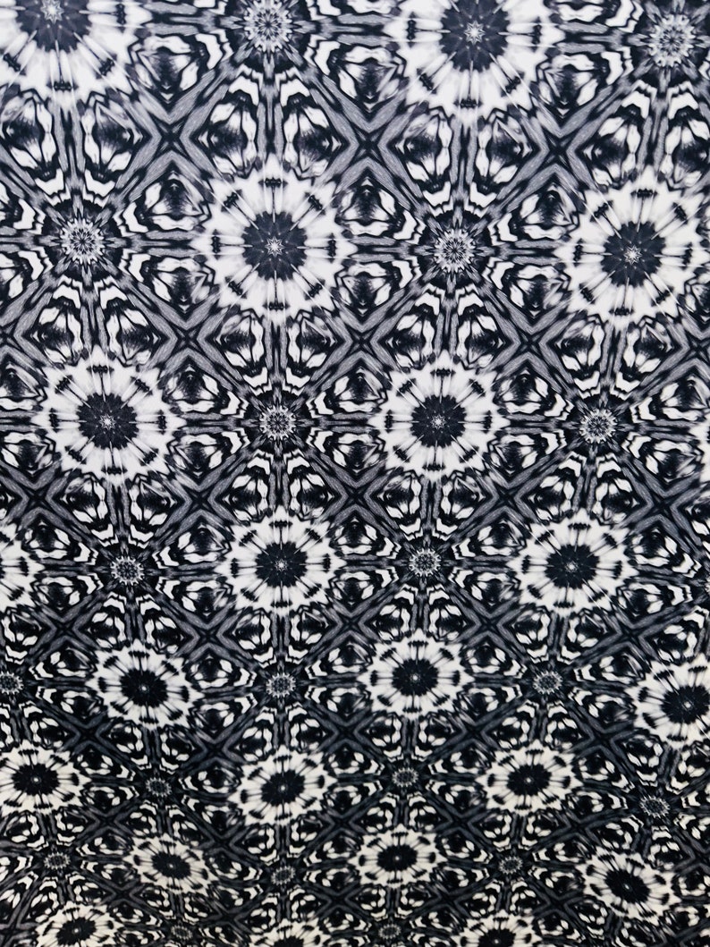 May include: Black and white fabric with a repeating geometric pattern of stylized flowers. The pattern is a gradient, with the flowers becoming more defined and darker at the bottom of the fabric.