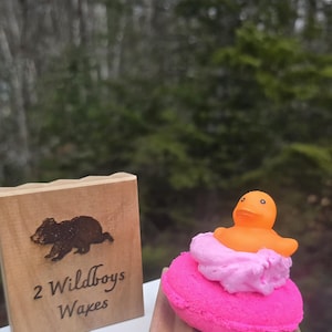 May include: A handmade wooden sign with the text "Welcome" in a handwritten style. The sign is painted white with a distressed finish and features a decorative floral design in shades of pink and green. It is designed to be hung on a wall.