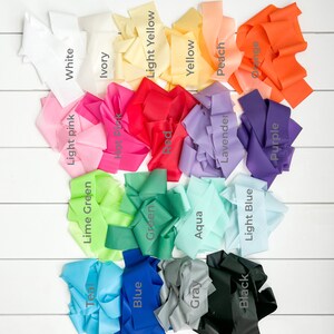 May include: A collection of 18 different coloured fabric ribbons, each with a label identifying its colour. The colours include white, ivory, light yellow, yellow, peach, orange, light pink, hot pink, red, lavender, purple, lime green, green, aqua, light blue, teal, blue, grey, and black.