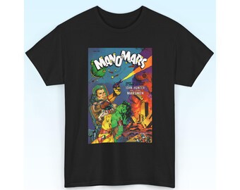 Può includere: Una t-shirt nera a maniche corte con una grafica di copertina di un fumetto vintage intitolata MANO-MARS. L'illustrazione raffigura un esploratore spaziale con casco e una figura dalla pelle verde, con il testo JOHN HUNTER AND THE MARSMEN.