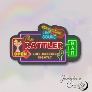 May include: Neon sign with the text "The Rattler Bar" in red, yellow, and blue. The sign also includes a cactus, a margarita glass, a guitar, and the text "Live Sound" and "Line Dancing Nightly".