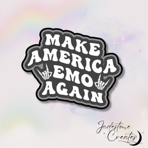 May include: A sticker with the text "MAKE AMERICA EMO AGAIN" in white, outlined in black and gray. The design includes skeleton hand gestures. The sticker has a black background and a gray border. The artist's signature is at the bottom.