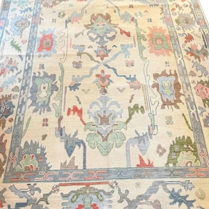 Pode incluir: Um tapete bege com um design persa tradicional. O tapete apresenta padrões florais intrincados em tons de azul, verde, vermelho e marrom. O tapete tem uma borda com um padrão geométrico repetitivo.