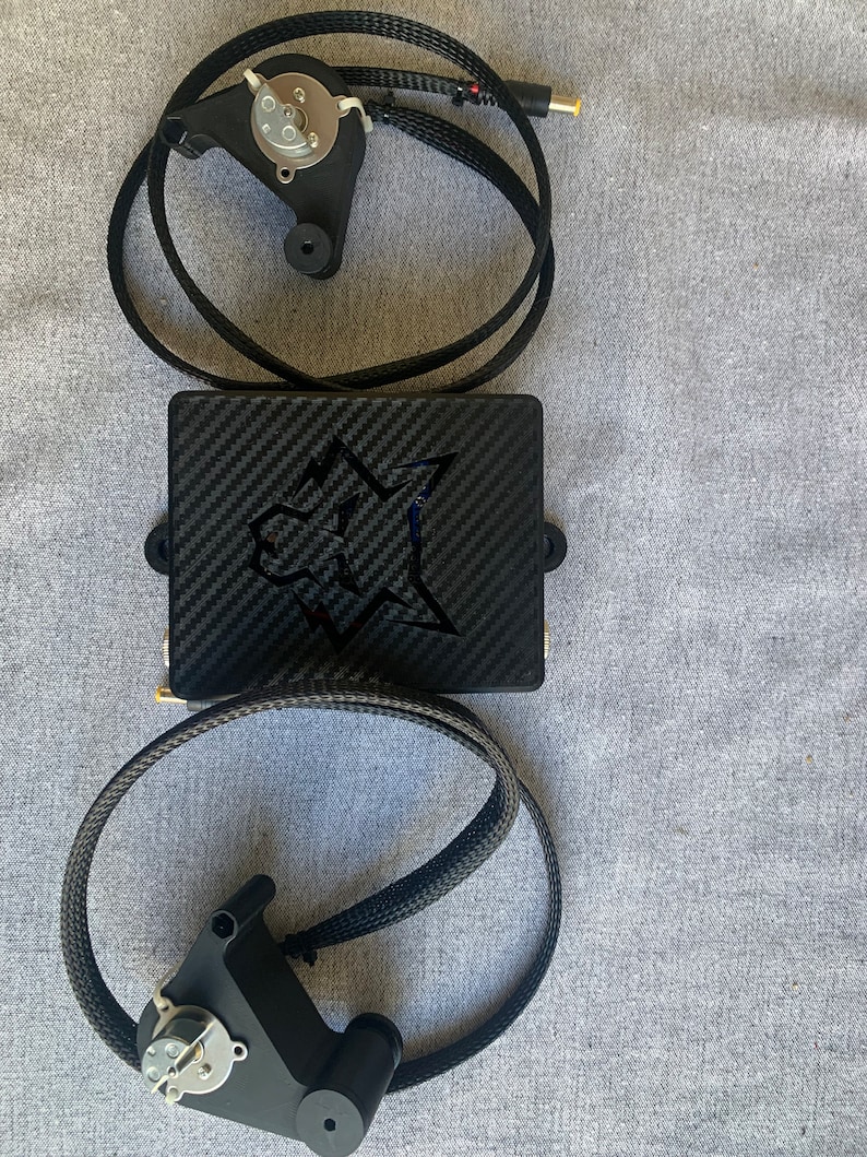May include: A black carbon fiber box with a white star logo and two black cables connected to a black motor with a silver gear.