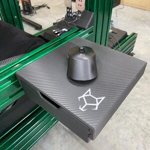 May include: A black carbon fiber tray with a drawer and a black mouse with a button labeled "RII". The tray is mounted on a green metal frame.