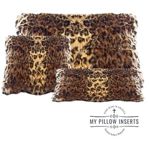 May include: Three leopard print throw pillows in various sizes. The pillows are made of faux fur and have a brown and tan color scheme. The pillows are arranged in a pyramid shape with the largest pillow at the bottom and the smallest pillow at the top. The pillows are all made by My Pillow Inserts.