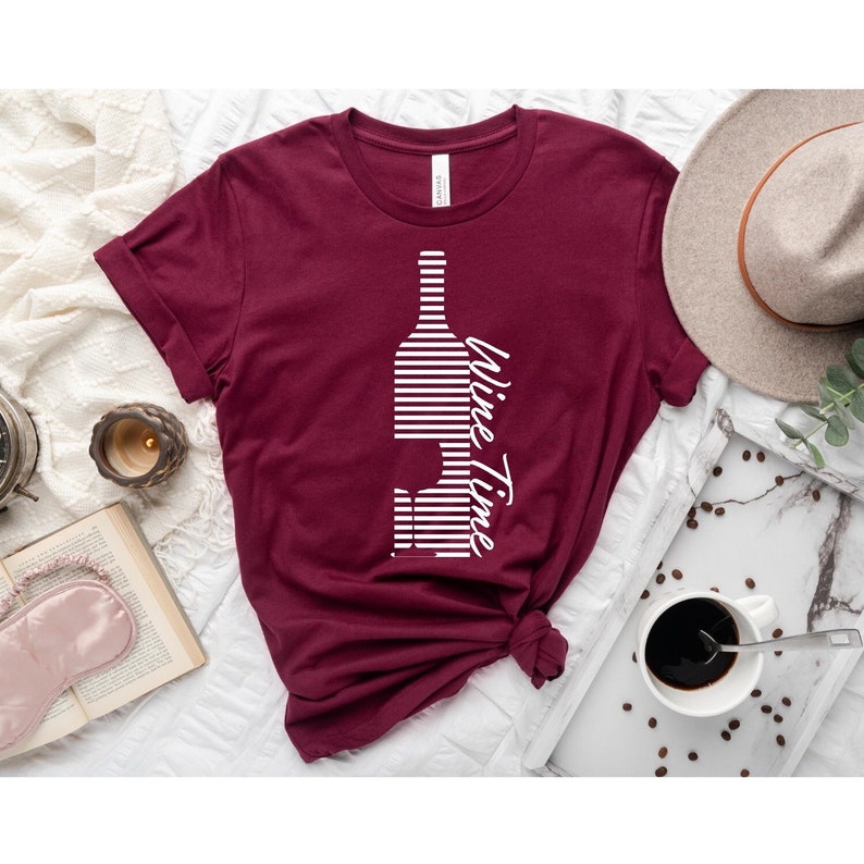 May include: A maroon t-shirt with a white graphic of a wine bottle and glass with the text "Wine Time" in a cursive font.