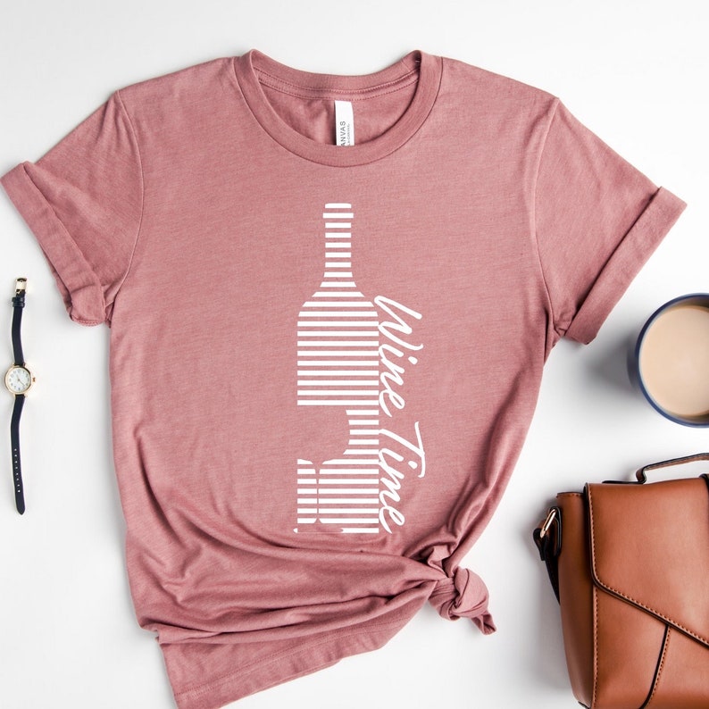 May include: A pink t-shirt with a white striped wine bottle and glass graphic and the text "Wine Time".