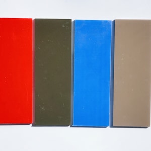 May include: Four rectangular pieces of plastic in different colors: red, dark green, blue, and light brown.