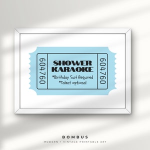 May include: A framed print with a light blue ticket design, displaying the words "SHOWER KARAOKE" in black. The ticket includes the text "*Birthday Suit Required *Talent optional" and the numbers "604760". The print is labeled "BOMBUS MODERN + VINTAGE PRINTABLE ART".