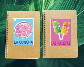 May include: Two brown notebooks with spiral binding. The left notebook has a sticker with a pink pastry and the text "25 LA CONCHA". The right notebook has a sticker with two popsicles and the text "13 LAS PALETAS".
