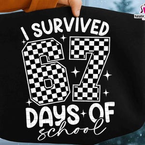 May include: Black tote bag with the text "I Survived 67 Days of School" in white. The numbers "67" are checkered. The bag is held by a person.