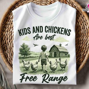 May include: White t-shirt with a green and brown illustration of a child and chickens in a field. The text "Kids and Chickens are best Free Range" is printed on the shirt.