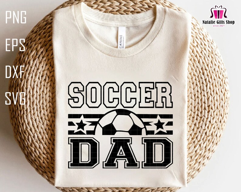K&ouml;nnte beinhalten: Ein wei&szlig;es T-Shirt mit schwarzem Text, der "Soccer Dad" mit einem Fu&szlig;ball und Sternen lautet.