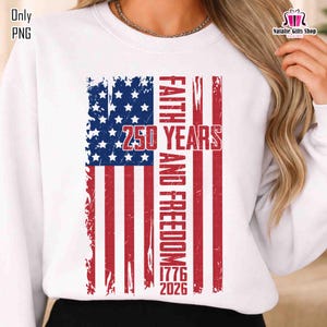 May include: White sweatshirt featuring a distressed American flag design. The flag incorporates the text "FAITH AND FREEDOM" and "250 YEARS 1776 2026" in red. The top has a crew neck and long sleeves.