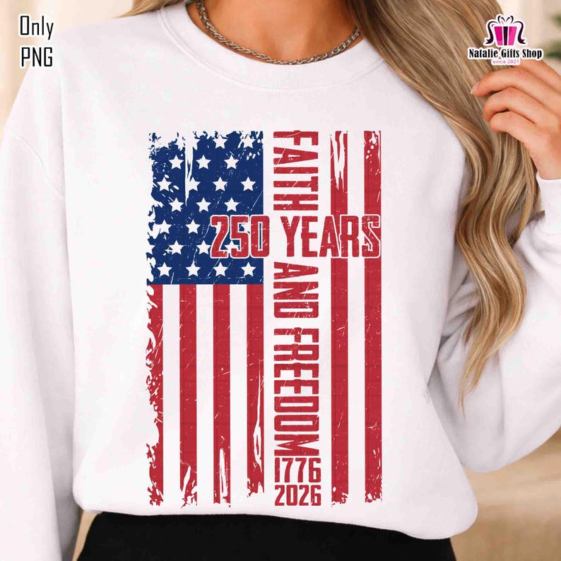 May include: White sweatshirt featuring a distressed American flag design. The flag incorporates the text "FAITH AND FREEDOM" and "250 YEARS 1776 2026" in red. The top has a crew neck and long sleeves.