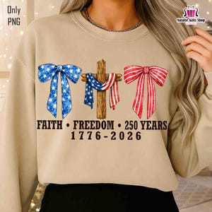 May include: Beige sweatshirt with patriotic graphics. Features a blue bow with white stars, a wooden cross draped with a red, white, and blue scarf, and a red and white striped bow. Text reads "FAITH &bull; FREEDOM &bull; 250 YEARS 1776-2026."