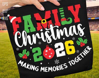 Può includere: Una t-shirt nera con il testo FAMILY CHRISTMAS 2026 MAKING MEMORIES TOGETHER in rosso, verde, bianco e giallo. Il design include un cappello da Babbo Natale, una gamba da elfo, una cintura, una pallina rossa, agrifoglio e fiocchi di neve.